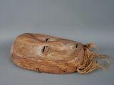 an old wooden mask with a rope around it ' s neck