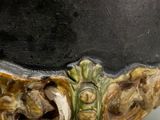 a close up of a black vase with a face on it