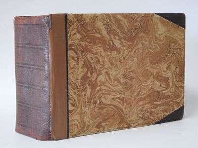 an old book sitting on top of a white table next to a white wall