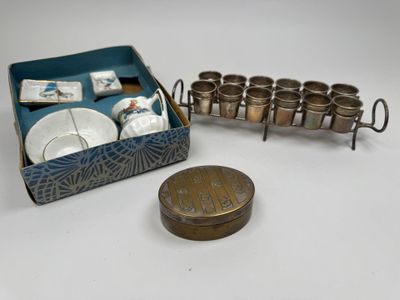 a box with cups and saucers and a coin on the table
