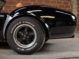 an image of a black sports car parked in front of a brick wall