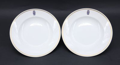 a pair of white plates with gold rims on a black background