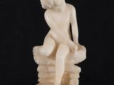 an image of a statue of a woman sitting on top of a rock