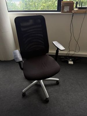 a black office chair sitting in front of a window