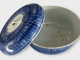 a blue and white bowl with a lid on a white surface