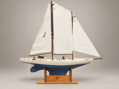 une petite maquette de voilier posée sur un socle en bois