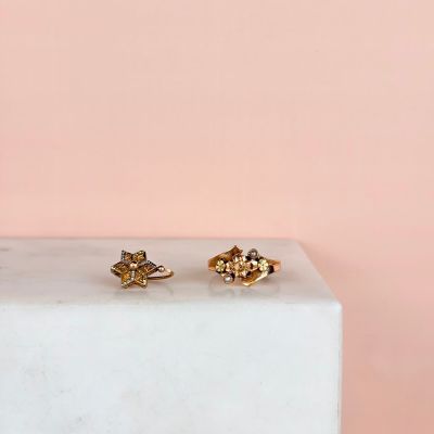 a pair of gold stud earrings sitting on top of a marble block