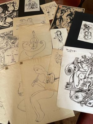 de nombreux dessins posés sur une table, avec une chaise rouge en arrière-plan