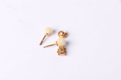 two pairs of earrings on a white surface with a white background