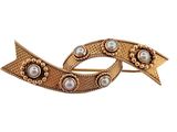 a close up of a brooch with pearls on it