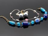 ensemble composé d'un bracelet et d'une paire de boucles d'oreilles, orné de perles de verre bleues et violettes sur un fond noir