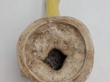 a small yellow vase with a brown handle on a white surface