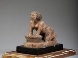a statue of a woman sitting on top of a wooden block