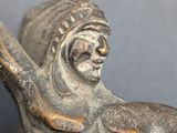 an old statue of a man holding a sword on a gray surface