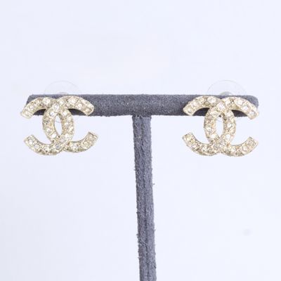 une paire de boucles d'oreilles Chanel posée sur un présentoir