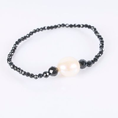 a black beaded bracelet with a white pearl and black beads