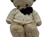 a brown teddy bear wearing a sweater and a black bow tie