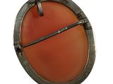an image of a round brooch with a red stone in the center