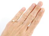 a woman ' s hand with a pearl ring on it