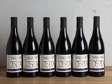 six bottles of red wine lined up on a wooden table