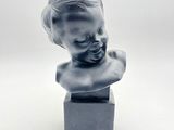 une petite statue représentant un enfant posée sur un petit socle