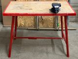 une table rouge sur laquelle est posé un morceau de bois