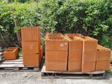 un tas de briques posé sur une palette à côté de quelques buissons