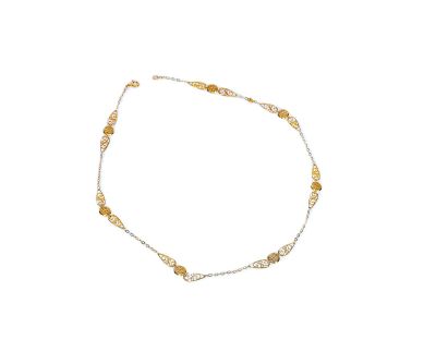 une chaîne de cheville en or et argent ornée de perles sur fond blanc