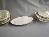 three pieces of white and gold china sitting on a table