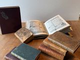 Plusieurs vieux livres sont posés sur une table en bois à côté d'une bibliothèque