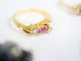two gold rings with pink stones and diamonds on a white surface