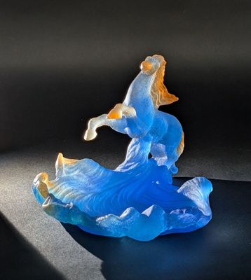 une figurine en verre représentant un homme à cheval sur une vague