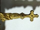 une croix en or sur le manche d'un objet en laiton