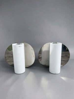 une paire de miroirs ronds avec des socles blancs posés sur un support gris