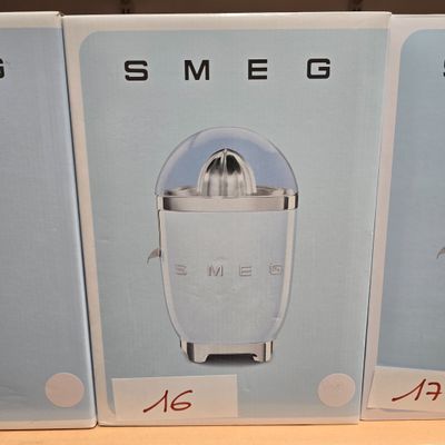 trois cartons contenant un extracteur de jus posés sur une table en bois