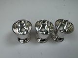 three silverplated cups and saucers on a white surface