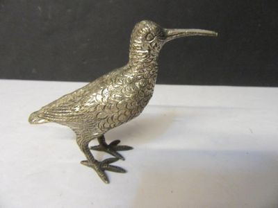 un oiseau argenté posé sur une surface blanche