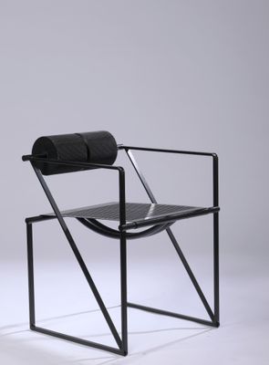 a black chair sitting on top of a white floor next to a white wall