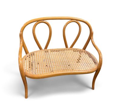 une image représentant un banc en bois avec des accoudoirs incurvés et une assise en osier