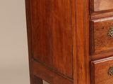 a small wooden chest of drawers on a white background