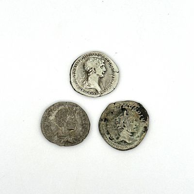 trois pièces de monnaie romaines antiques posées sur une surface blanche, sur fond blanc