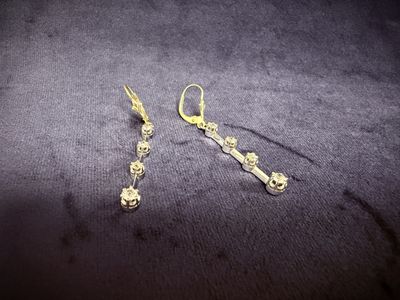 two pairs of gold plated earrings on a black surface