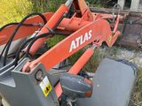 une pelleteuse orange garée dans l'herbe à côté d'un bâtiment