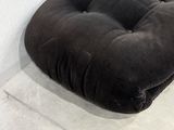 a black cushion on the floor in the corner of a room