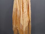 a yellow shawl with fringes on a mannequin stand