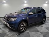 Une Dacia bleue est garée dans une pièce au sol à carreaux.