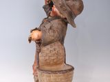a statue of a man with a hat and a basket on his head