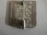 a silver broocht with a pin on it