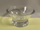 un saladier en verre posé sur une nappe jaune, sur une table