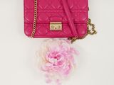 pink quilted purse with a flower on a white background